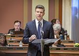 Representative Winkler stands at the Majority Leader's podium in the House Chamber and speaks to someone out of view.